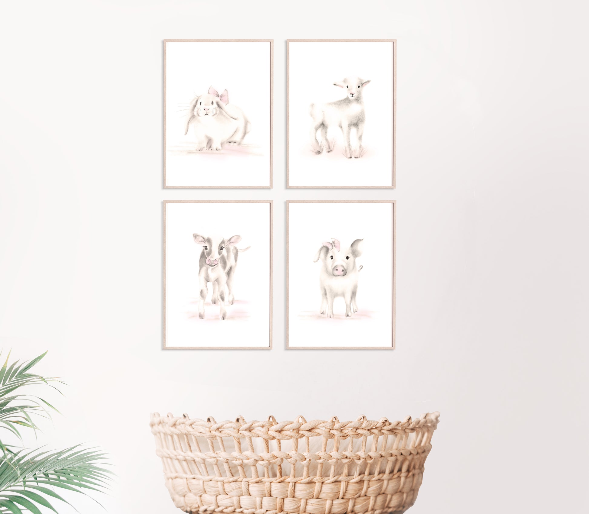Set of 4 baby farm animal sketch prints in shades of beige and pink on white backgrounds. Prints are framed in light woodtone frames and hang on a plain wall above a baby basket basinette. Studio Q - Art by Nicky Quartermaine Scott