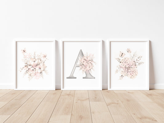 Set of three flower and butterfly sketches in tones of beige and blush pink. Center print has a letter A designed with flowers. Prints are mounted in white frames and sit on a wood floor - Studio Q - Art by Nicky Quartermaine Scott  